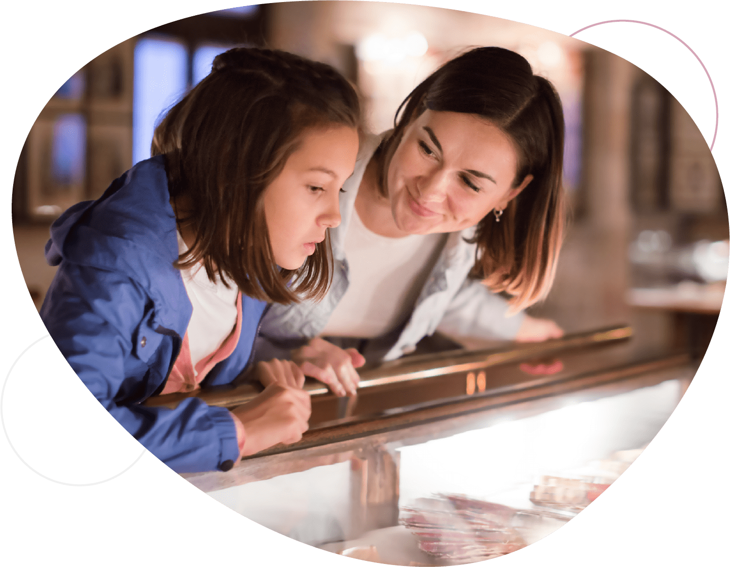 Mom and young daughter looking at items in museum glass